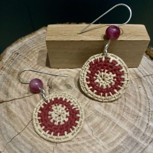 Hand-dyed hand-woven raffia earrings, hanging from hand-formed Argentium Silver hooks, with gemstones. Displayed on The Raffia Kat gift card. Dyed with avocado pit and coiled with burgundy cotton. Features dark, pink-coloured gemstones