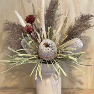 Large banksia arrangement in camel necked vase